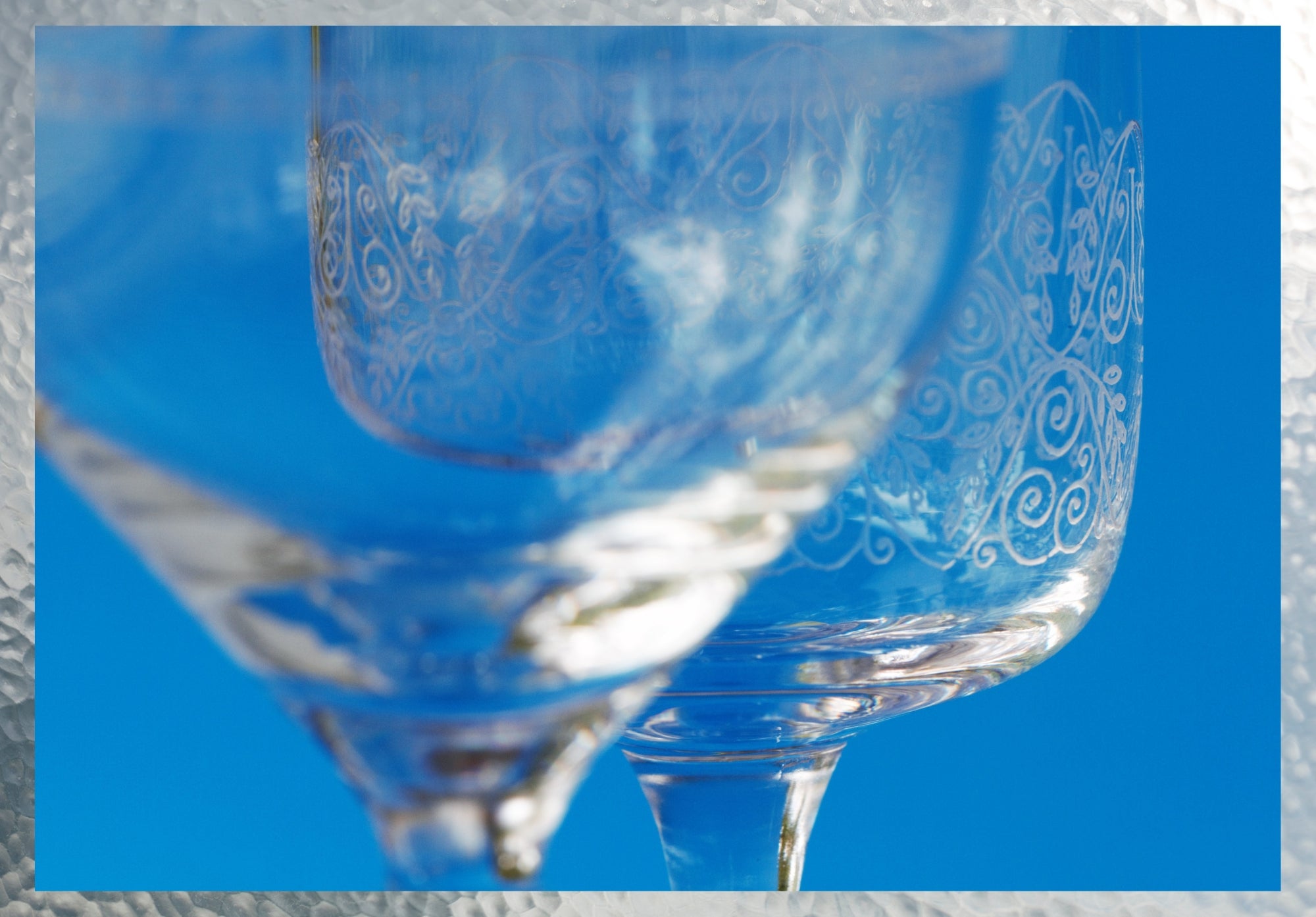 Image of wine glasses with decorative etchings against bright blue background