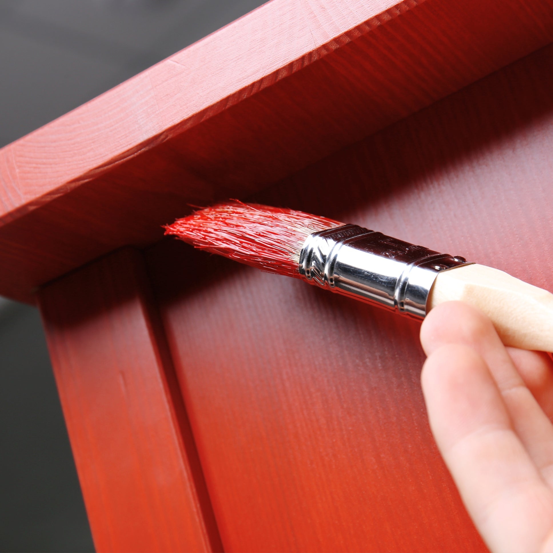 Burnt orange paint being applied to furniture with brush.