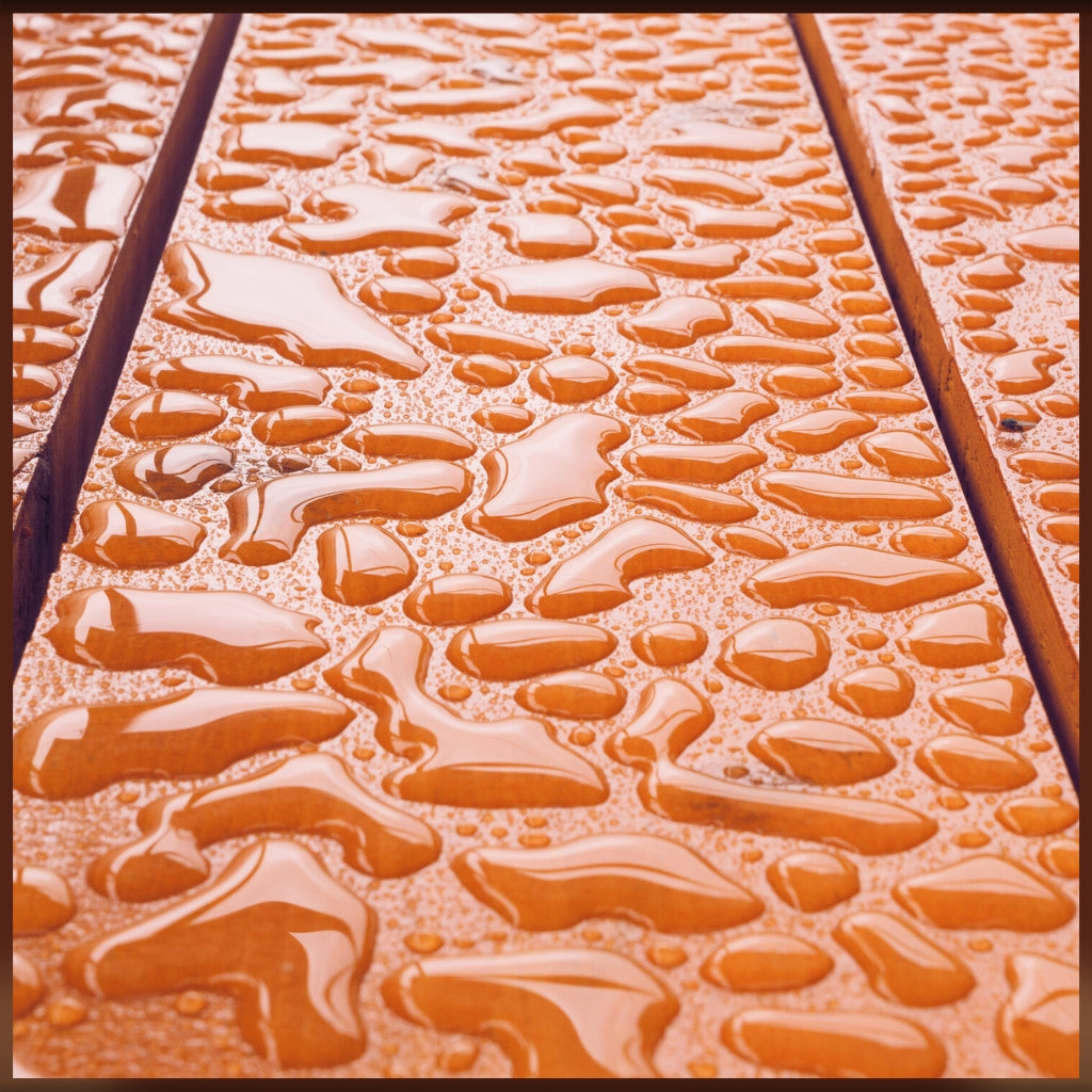 Image of water droplets repelling off varnished wood surface with slats.