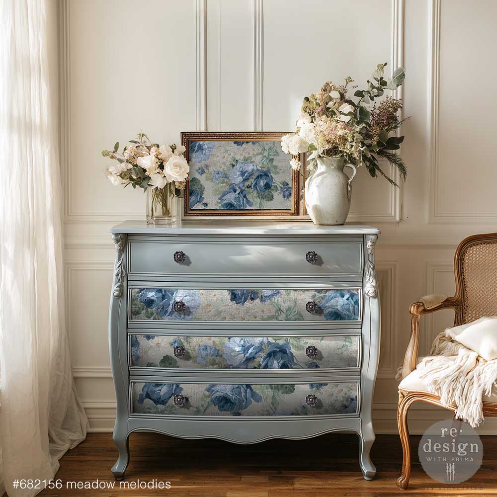 Decorative chest of drawers with floral design in a room with flowers and a chair.